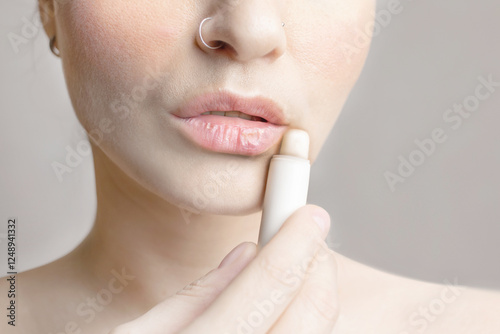 Woman dyes her lips with moisturizing balm. Woman with dry lips, dry skin problem. Close up photo