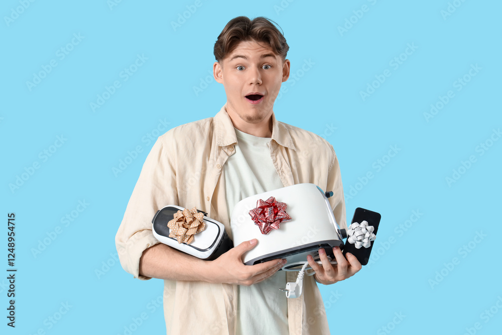 Surprised young man with gift appliances on blue background Surprised young man with gift appliances on blue background