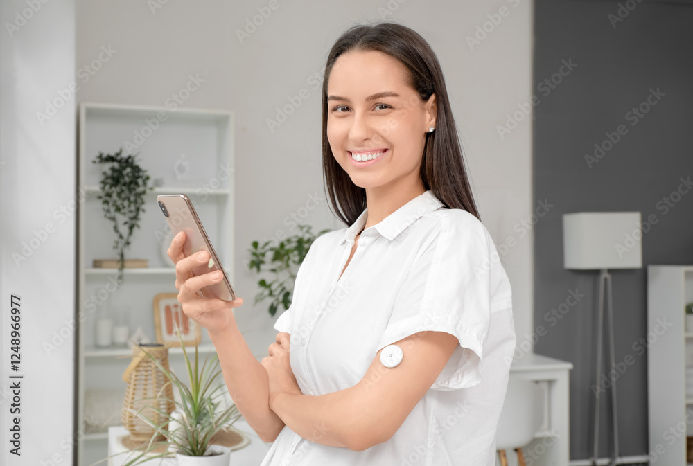 Diabetic young woman with glucose sensor and mobile phone at home