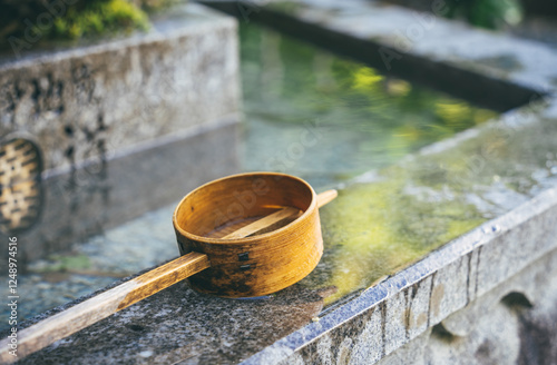 Isolated traditional japanese bamboo wooden laddle. Purification water fountain chozubachi. photo