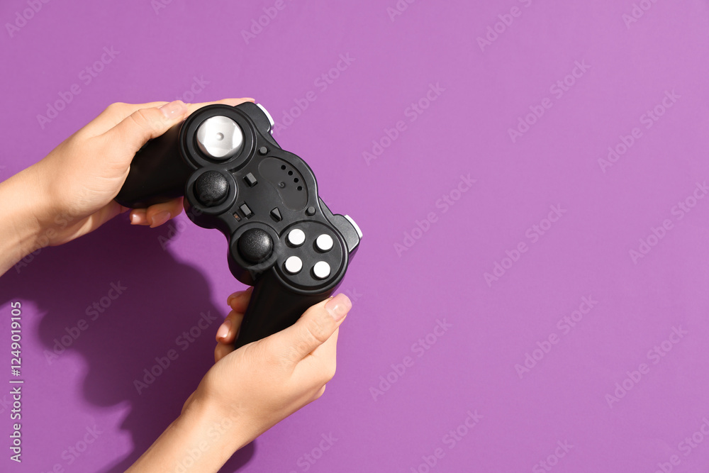 Female hands with modern game pad on purple background, closeup