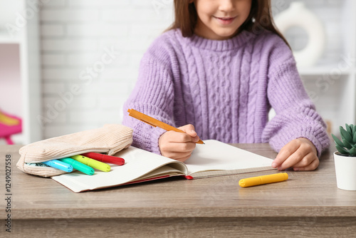 Cute little happy girl with pencil case, markers and notebook drawing at home...