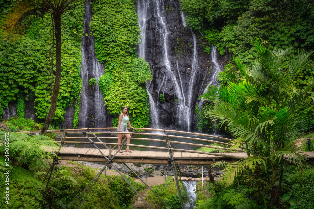 Obraz premium A woman on a bridge discovers and explore a breathtaking Banyumala Twin Waterfalls embraced by lush greenery, ideal destination for both nature enthusiasts and adventure seekers alike, Bali, Indonesia