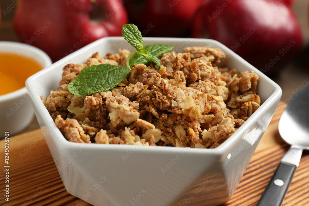Tasty apple crisp in bowl, ingredients and spoon on table, closeup Tasty apple crisp in bowl, ingredients and spoon on table, closeup