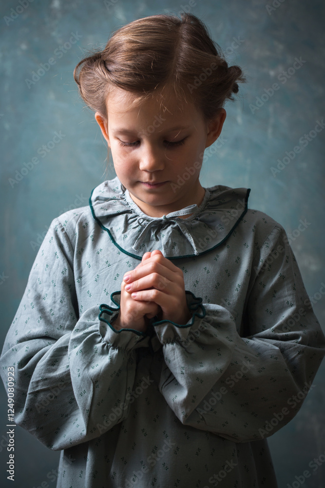 A girl prays with her hands folded together