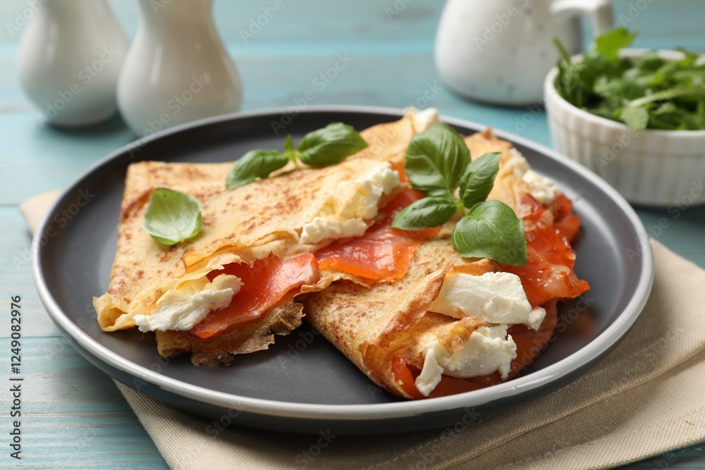 Delicious crepes with salmon, cream cheese and basil on light blue wooden table, closeup Delicious crepes with salmon, cream cheese and basil on light blue wooden table, closeup