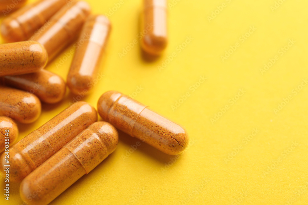 Turmeric capsules on yellow background, closeup. Space for text Turmeric capsules on yellow background, closeup. Space for text