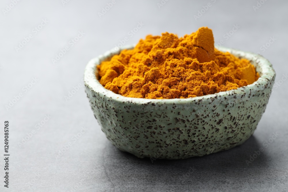 Turmeric powder in bowl on grey table, closeup Turmeric powder in bowl on grey table, closeup