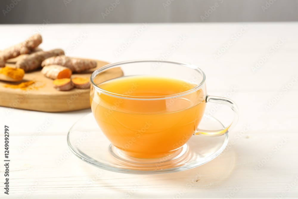 Aromatic turmeric tea in glass cup, roots and powder on white wooden table, closeup Aromatic turmeric tea in glass cup, roots and powder on white wooden table, closeup