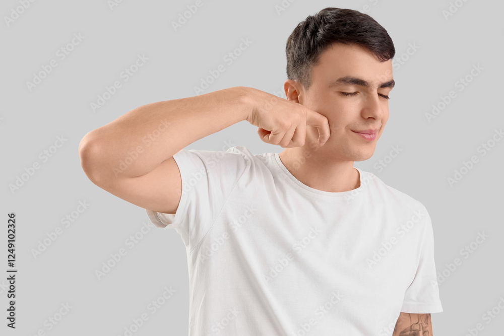 Young man doing face building exercise on light background