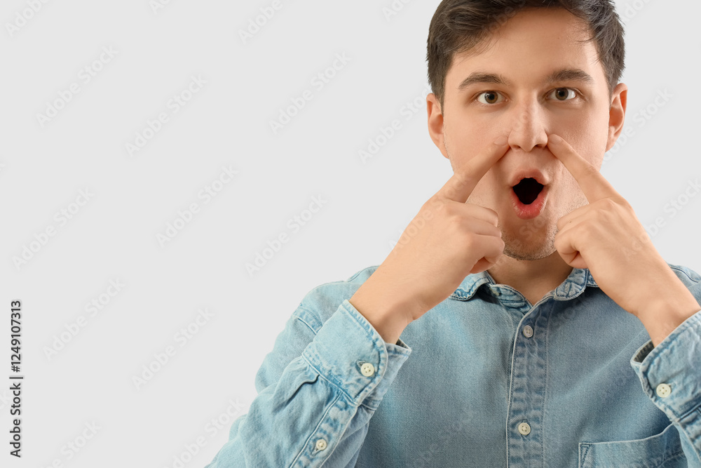Young man doing face building exercise on light background
