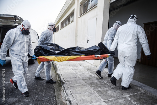 Bild auf Leinwand Funeral Home employees wear protective suits to protect themselves from Coronavirus, as they carry a dead body inside a Bag