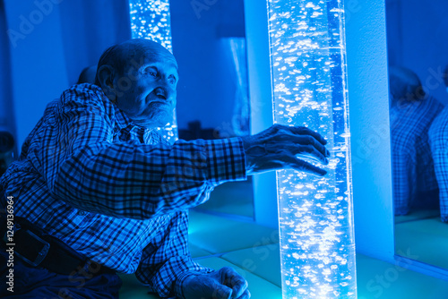Elderly man engaging with sensory light tube
