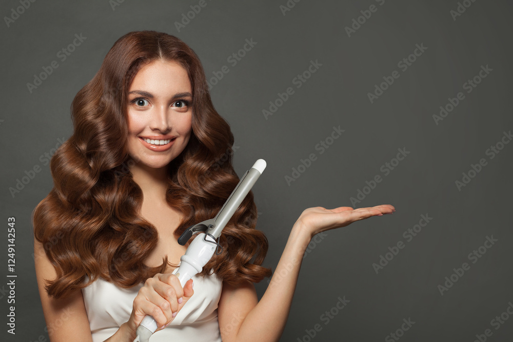 Obraz premium Healthy brown haired woman with shiny long curly hairstyle showing curling iron. Hair treatment, hair care and styling
