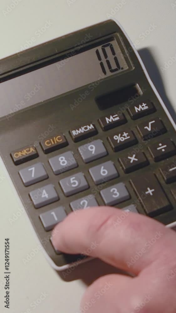 Close-up of a man's hand pressing numbers on a calculator-vertical Close-up of a man's hand pressing numbers on a calculator-vertical