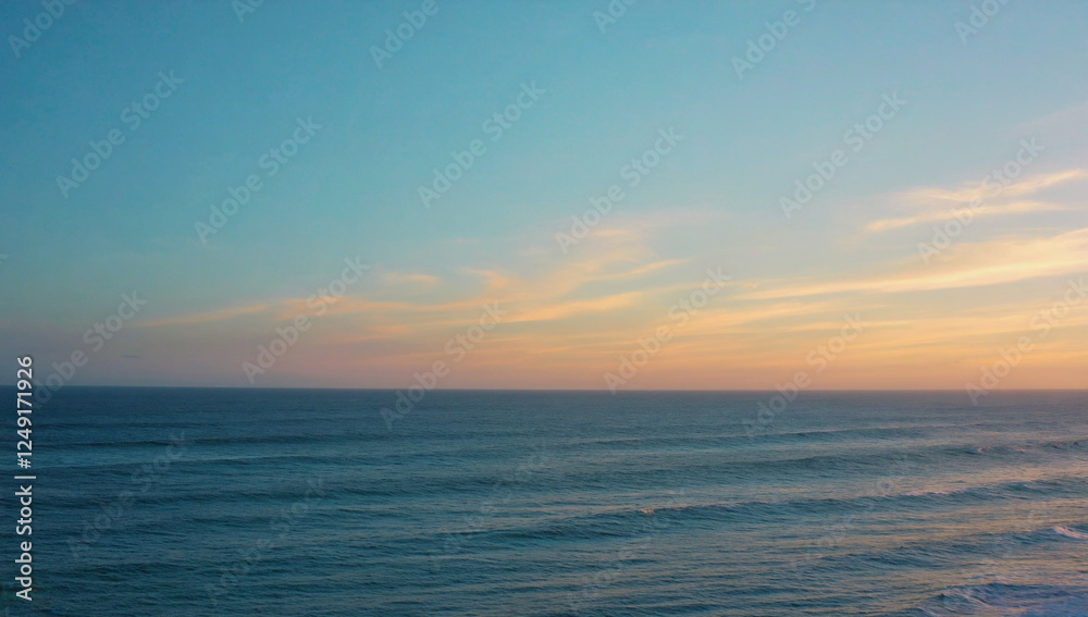 Fototapeta premium Ocean Sunset Horizon: A serene seascape captures the beauty of a pastel sunset as it paints the sky with hues of pink and orange, while the deep blue ocean stretches into the distance.