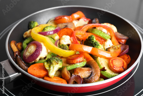 Frying pan with mix of vegetables and mushrooms on cooktop, closeup