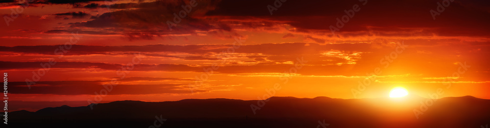 Wide panorama of a glowing orange striped sunset sky Wide panorama of a glowing orange striped sunset sky