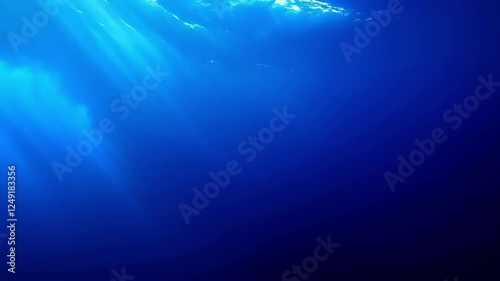 The water is blue and clear. There is a sunbeam shining through the water. The water is calm and still