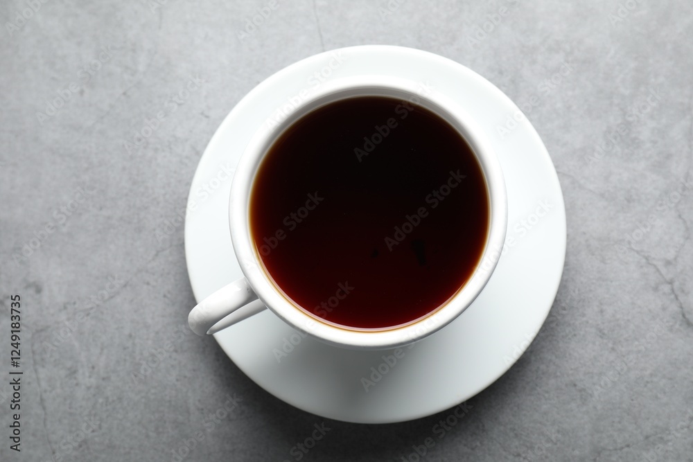 Refreshing black tea in cup on grey textured table, top view Refreshing black tea in cup on grey textured table, top view