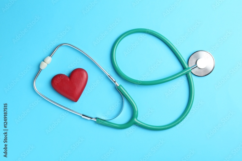 Cardiology. Stethoscope and red decorative heart on light blue background, flat lay Cardiology. Stethoscope and red decorative heart on light blue background, flat lay