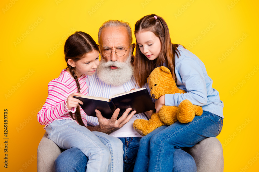 Elderly man reading a book to two young girls with a yellow background Elderly man reading a book to two young girls with a yellow background