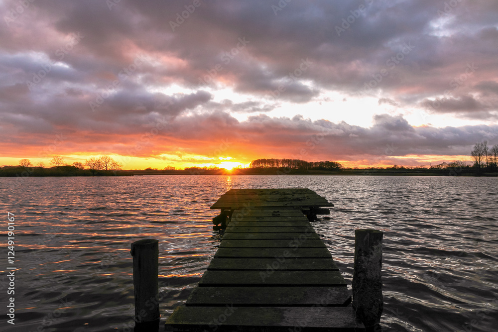 jetty at the lake with dramatic sky at sunset.