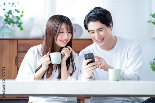 リビングでスマホを見て笑顔の日本人男女