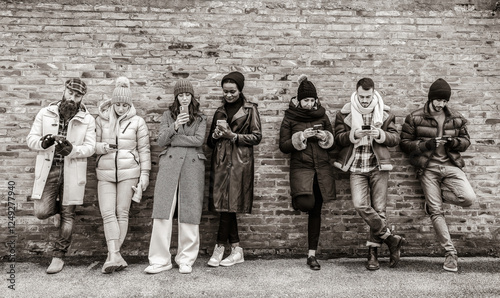 Bilde på lerret Group of diverse individuals leaning against a brick wall, absorbed in their smartphones