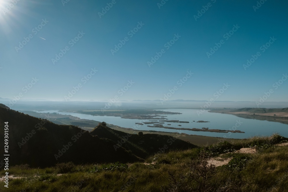 Tranquil lake and rolling hills under a clear sky Tranquil lake and rolling hills under a clear sky