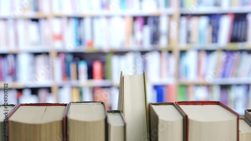 Close-up of woman hand finding a book on bookshelf in the library