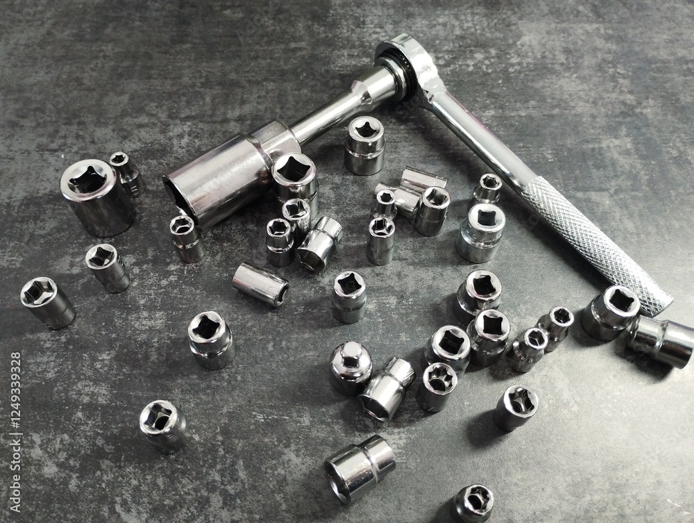 Metal set of heads and wrenches. Wrenches and interchangeable heads of different diameters for unscrewing bolts. Repair tools are scattered chaotically on a dark background. Metal set of heads and wrenches. Wrenches and interchangeable heads of different diameters for unscrewing bolts. Repair tools are scattered chaotically on a dark background.