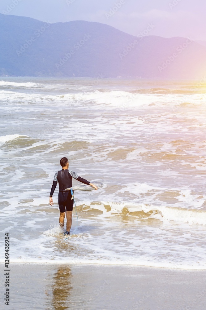 Young asian male surfer entering ocean waves on sunny day Young asian male surfer entering ocean waves on sunny day