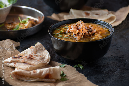 Vegan split yellow pea soup with caremelized onions, flat breads.  Black background, copy space photo