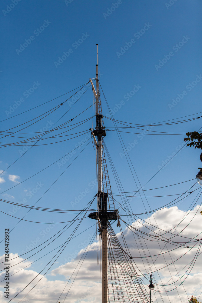 Masts of an old sailing ship against a blue sky. Old sailing boat rigging