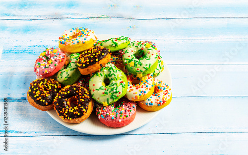 Colorful donuts on a white plate on a blue wooden background