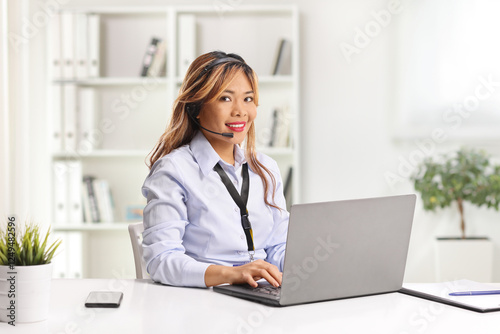 Asian woman working on a laptop computer with wireless handsfree headphones