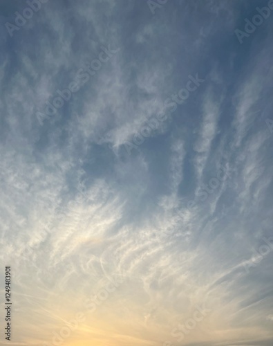 A serene sky with delicate wispy clouds illuminated by the warm hues of the setting sun, creating a peaceful and dreamy atmosphere.   photo