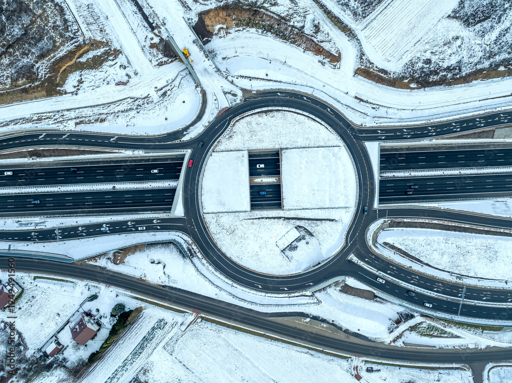 Traffic circle with a hole. Multilevel junction under construction over new highway S52 opened for traffic in December 2024 in Krakow, Poland. Aerial view from above in winter with snow