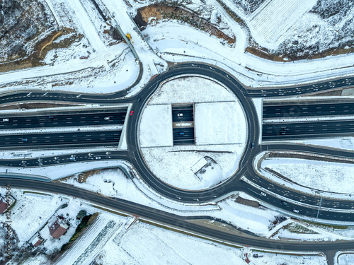 Obraz na płótnie Traffic circle with a hole. Multilevel junction under construction over new highway S52 opened for traffic in December 2024 in Krakow, Poland. Aerial view from above in winter with snow w salonie