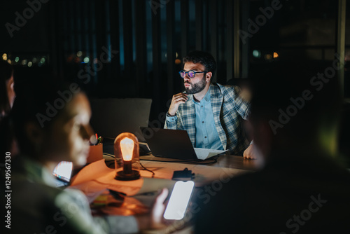Fotografie Focused professionals work late in a dimly lit office, collaborating intensely on a project