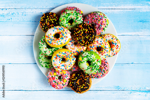 Colorful donuts on a white plate on a blue wooden background