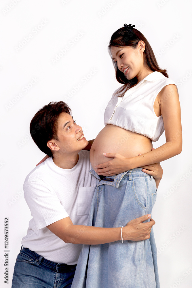 Happy family Asian couple on white background, husband is embracing his wife, listening to her tummy. Mother gently touch her belly. Beautiful smiling pregnant woman mother with big tummy. Happy family Asian couple on white background, husband is embracing his wife, listening to her tummy. Mother gently touch her belly. Beautiful smiling pregnant woman mother with big tummy.