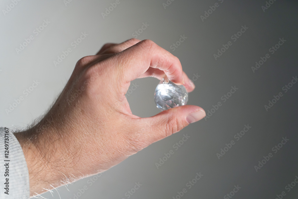 Hand Holding a Diamond on Grey Background Hand Holding a Diamond on Grey Background