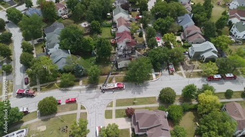 Wide Shot of a burned house in suburbs and firemen putting water on fire. Top down drone shot