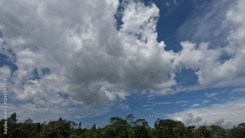 Timelapse of fluffy white clouds above the trees during the day. White clouds rolling and rolling fast with a blue sky background. Climate and weather concept. Footage 4k, Raw video no edit Timelapse of fluffy white clouds above the trees during the day. White clouds rolling and rolling fast with a blue sky background. Climate and weather concept. Footage 4k, Raw video no edit