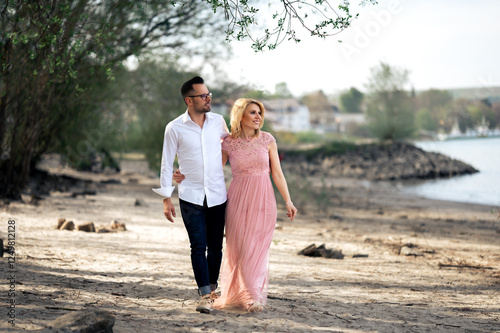 Couple in love walking on the beach, happy pair on beach, photo of the young family, woman in long pink dress and man outdoors, lovely couple, people in love, engagement photography