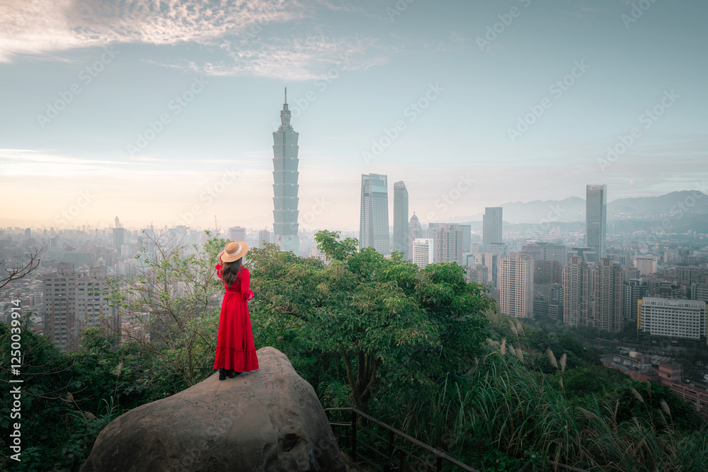 Fototapeta premium Beautiful asian woman in red dress and hat standing on the peak of Hong Kong city at sunset 
