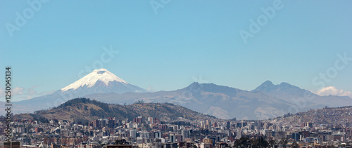 Vista panorámica de Quito con el icónico Volcán Cotopaxi de fondo, capturada desde la parte norte de la ciudad bajo un cielo despejado, Ecuador.