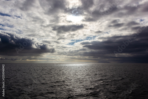 Atardecer cálido sobre el océano Pacífico, se aprecia un rayo de luz y nubes, Galápagos, Ecuador. photo